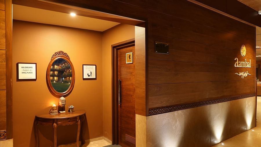 Warmly lit entrance to a spa or wellness centre, featuring wooden decor, a round mirror, framed artwork, and soft ambient lighting at Uday Backwater Resort