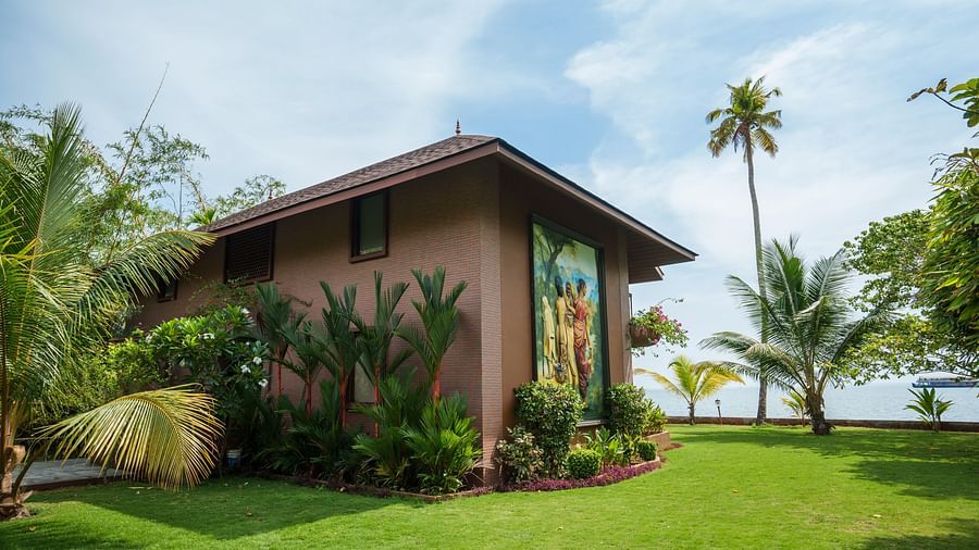 Facade of Uday Backwater Resort on a sunny day featuring lush lawn and trees grown around the building and in its vicinity
