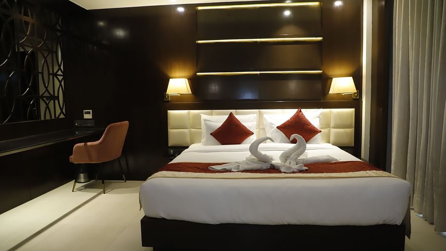 Junior Suite featuring a plush bed on which towels are decorated into two swans and a chair next to the window in the background
