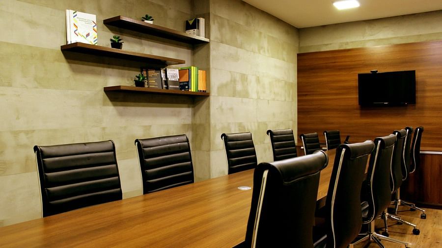 Shot of a boardroom with a long table and several chairs and shelves on the wall.