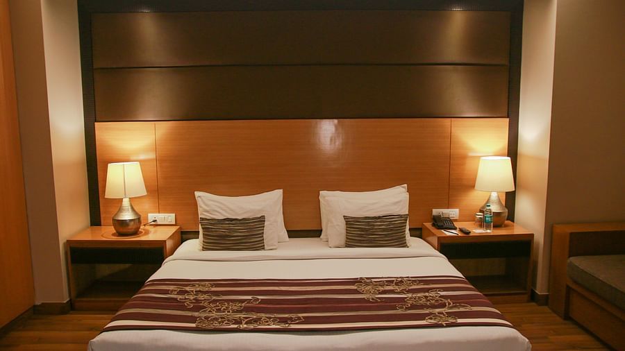 An image of a room in dim lighting featuring a plush bed with lamps on the nightstands on both sides