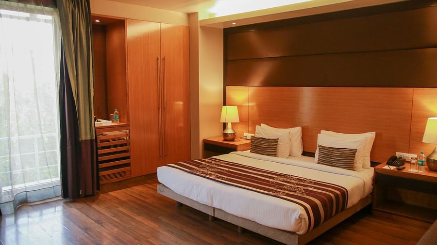 A well-lit room featuring a plush bed with lamps on both sides on the nightstand and a large window