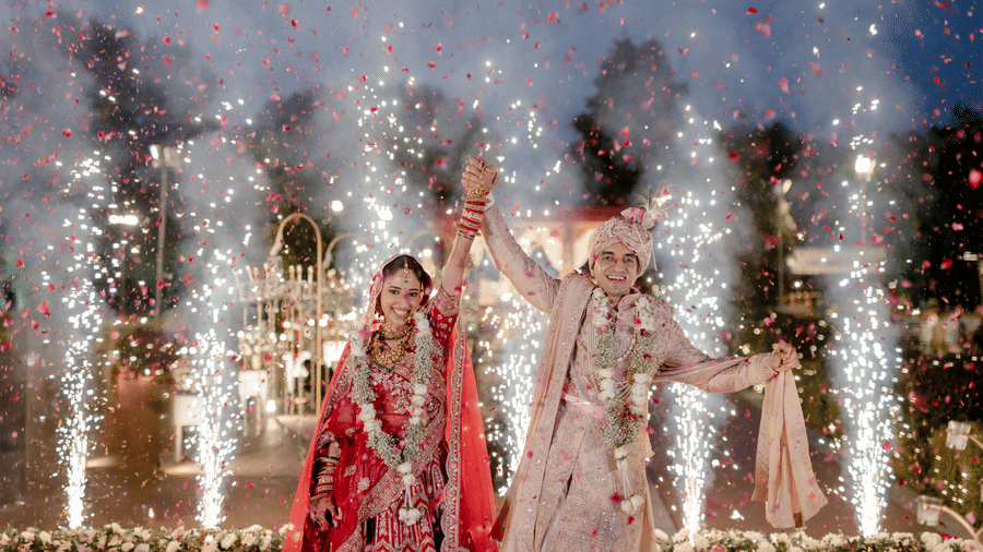 Bride and groom making a grand wedding entry with fireworks at Umaid Palace.