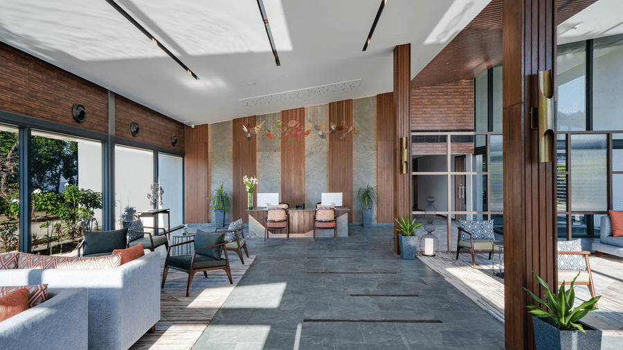 A spacious lobby at Vandhara Sarovar Premiere, Patkote, with floor-to-ceiling windows, modern seating, and views of the mountains.