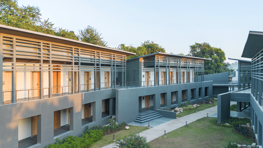 Exterior view of the multi-storey guest wing at Vandhara Sarovar Premiere, Patkote, featuring stone walls and large windows.