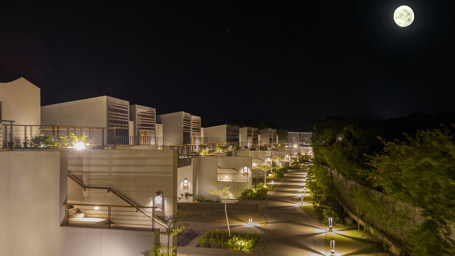 Night view of the landscaped pathways and guest buildings at Vandhara Sarovar Premiere, Patkote, under a bright moon.