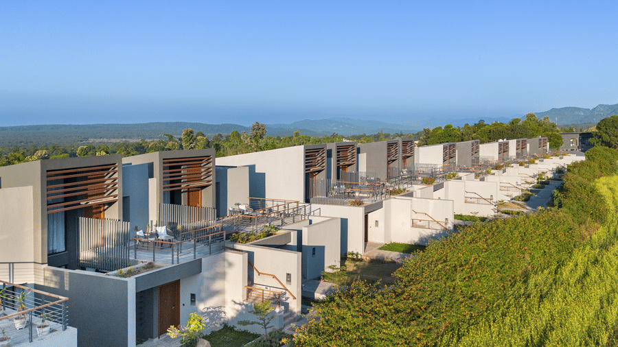 An elevated view of the terraced Villas at Vandhara Sarovar Premiere, Patkote, with wooden slats on balconies overlooking greenery.