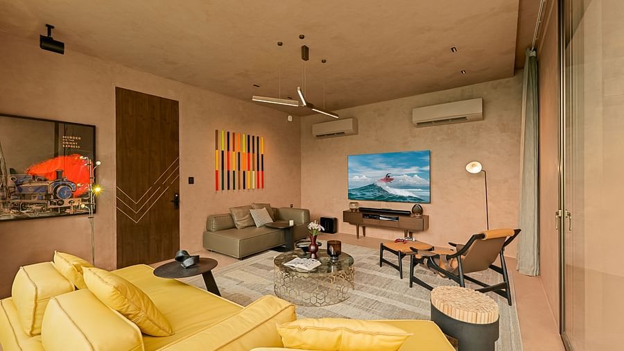 The spacious living room at Villa Moira by V Escapes, with a vibrant yellow sofa, eclectic artwork along with a wall mounted television, and a relaxed, inviting atmosphere.