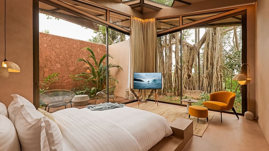 A spacious bedroom at Villa Moira by V Escapes, with a comfortable double bed, large windows looking out to lush trees, and modern furnishings.