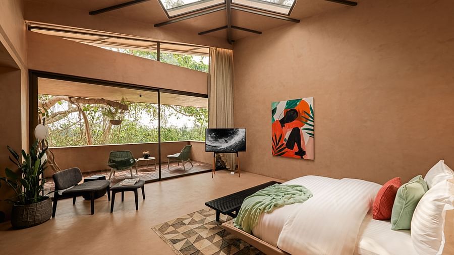 A spacious bedroom at Villa Moira by V Escapes, featuring a double bed, large windows, a skylight, and abstract artwork on the wall.