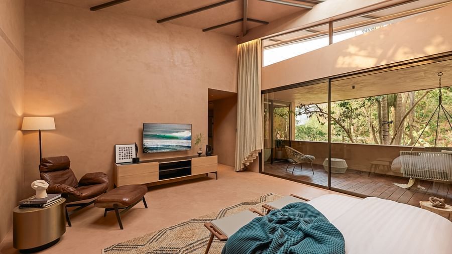 A cosy living area at Villa Moira by V Escapes, with comfortable armchairs, a large window showcasing outdoor views, and a television.