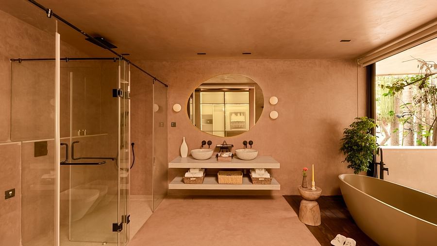 A luxurious bathroom at Villa Moira by V Escapes, with a double vanity, large mirrors, a glass-enclosed shower cubical, and full length bathtub.
