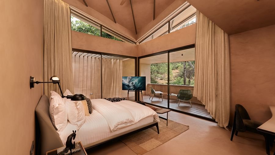 A serene bedroom at Villa Moira by V Escapes, boasting a high ceiling, a comfortable double bed, and expansive views through large sliding doors.