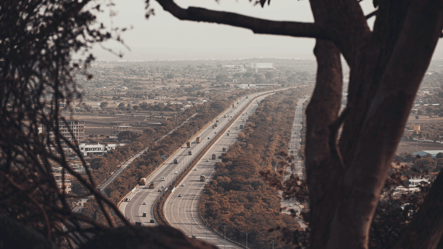 A highway cuts through hilly terrain with trees and distant landscape views.