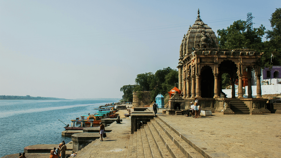 A view of the Narmada River on the left and steps leading to the river on the right hand side with a temple on it. The number of Narmada Parikrama walking days differ to your pace, it might take 200 days to 3 years, 3 months and 13 days.
