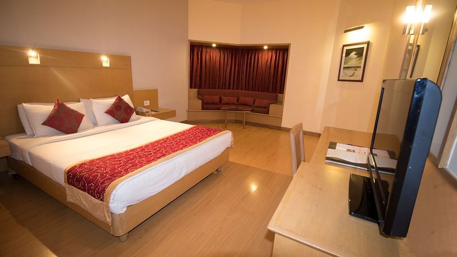 A king bed with a tv opposite it inside the Deluxe Rooms at VITS Nanded Hotel