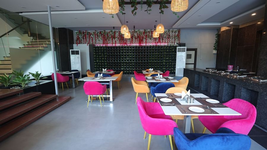 A dining area with colourful chairs, set tables, and hanging lights, creating a vibrant atmosphere - VITS Gurugram