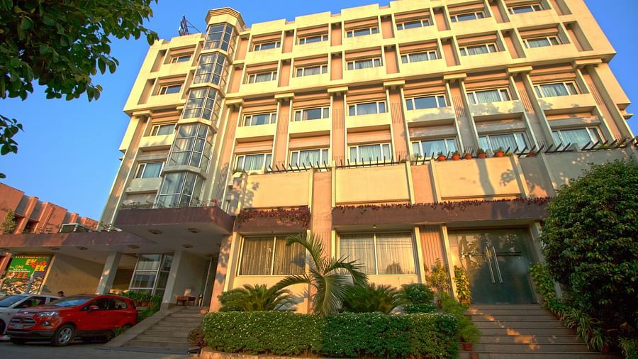 Huge cream coloured building in Bhubneshwar with cars standing in the parking area