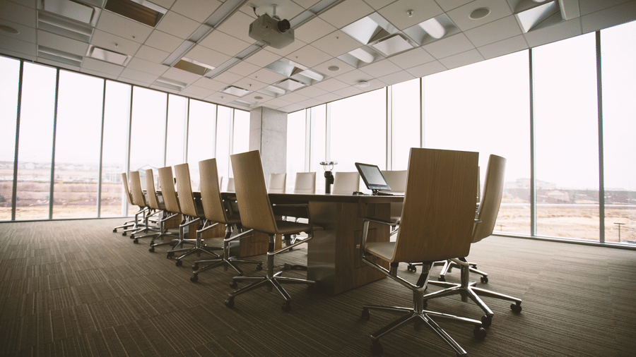A rectangle shaped table with chairs in a conference hall with floor to ceiling windows