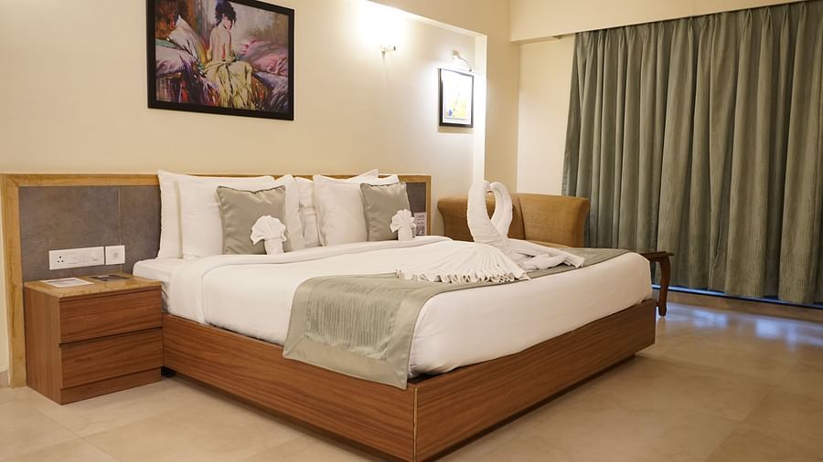 Double bed room with bedside table, ceiling-to-floor windows, and a seating area at VITS Kamats Resort, Silvassa