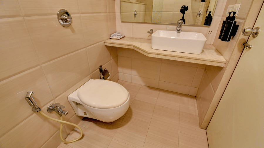 Modern bathroom with washbasin, toilet, and beige tiled walls at VITS Lonavala.