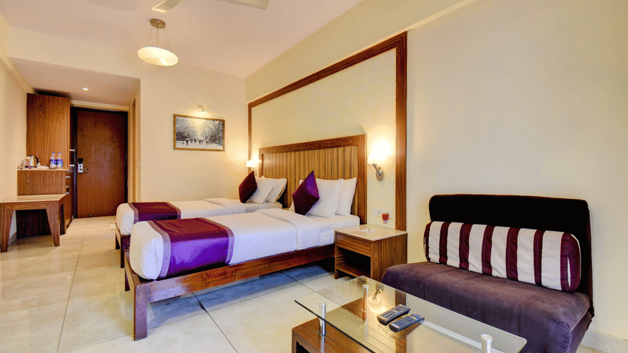 Premium room with bed, sofa seating, and glass coffee table at VITS Lonavala.