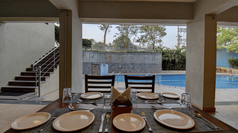 Poolside dining area with neatly arranged table settings at VITS Lonavala.
