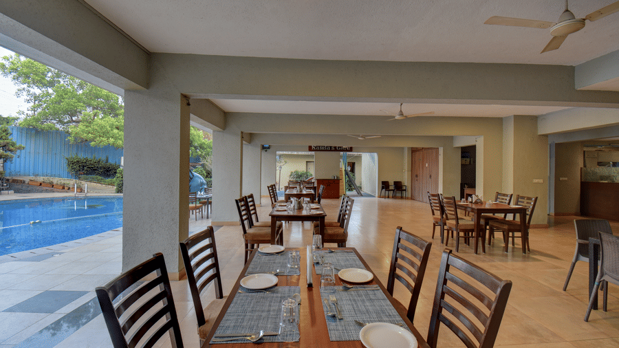 Spacious indoor restaurant with wooden tables and pool view at VITS Lonavala.