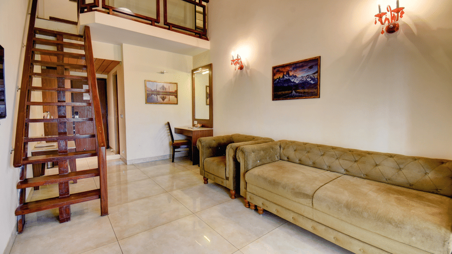 Duplex suite living area with staircase and comfortable sofa at VITS Lonavala.