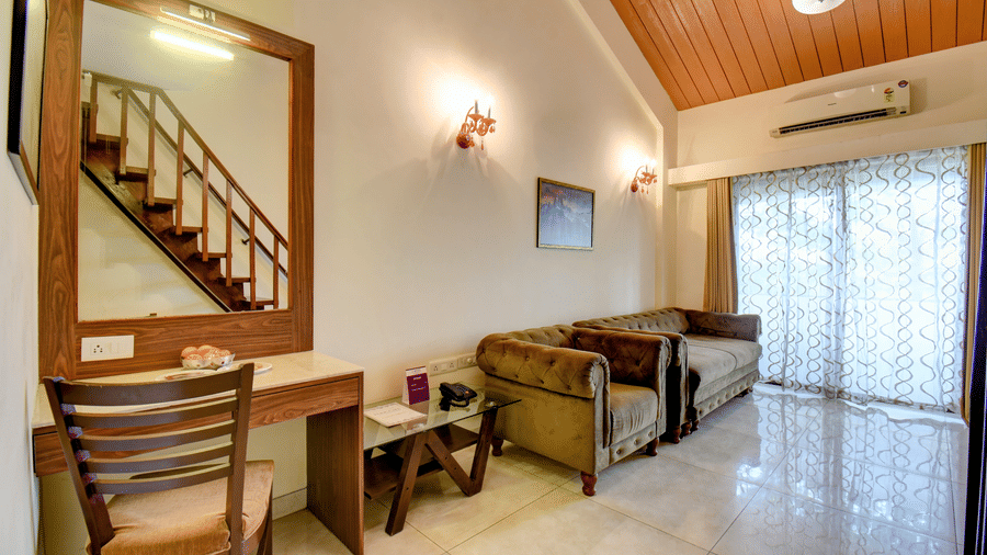 Spacious suite with work desk, sofa seating, and balcony access at VITS Lonavala.