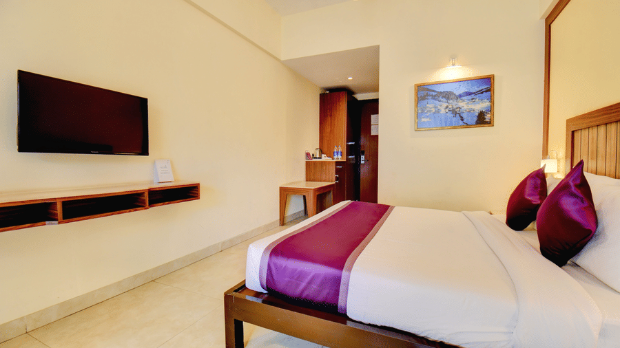 Contemporary hotel room with wall-mounted TV and elegant bedding at VITS Lonavala.