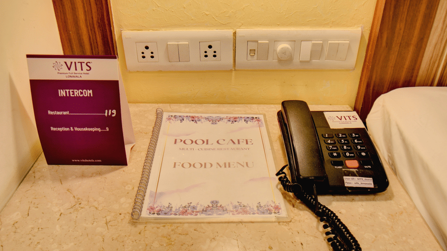 In-room amenities including telephone, notepad, and information card at VITS Lonavala.