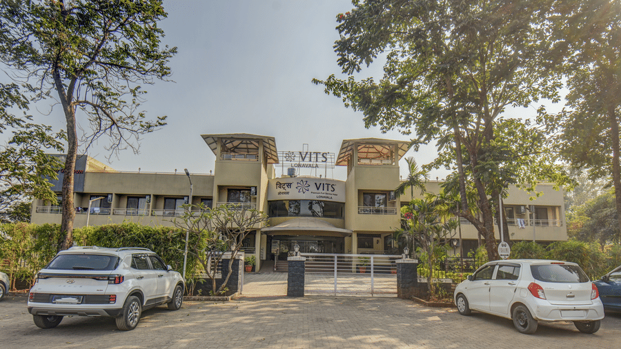 Front view of hotel entrance with parked cars at VITS Lonavala.