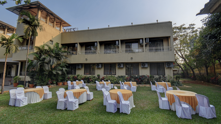 Open lawn event space with round tables and resort building view at VITS Lonavala.