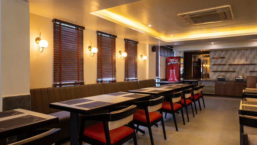 A close-up of a dining section at VITS Select, Bengaluru, featuring upholstered bench seating with individual tables and chairs - one of the best restaurants in Hebbal