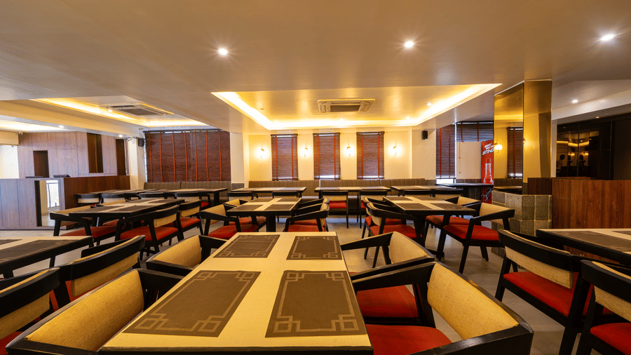 A pleasant, organised dining room at VITS Select, Bengaluru, showcasing neatly arranged tables and chairs across the spacious interior.