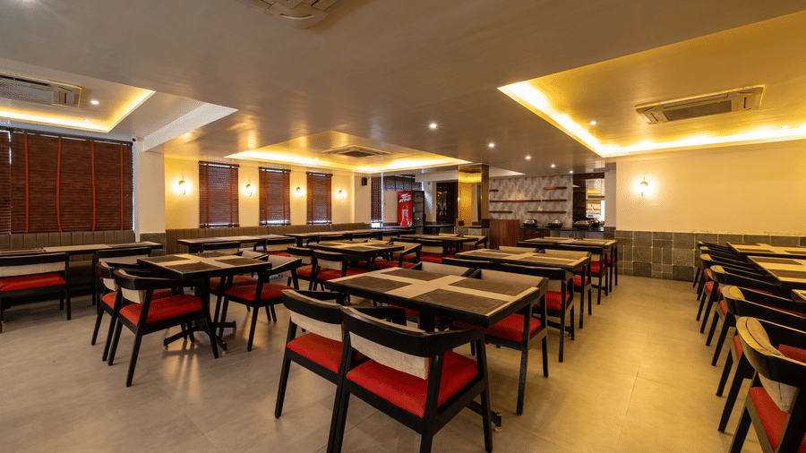 A wide-angled view of the clean dining hall at VITS Select, Bengaluru, with rows of tables, chairs, and soft cove lighting - one of the best restaurants in Hebbal.