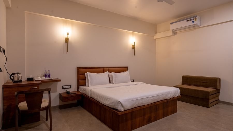 A double bed with sofas on the side and a study table in the other side inside one of the rooms - VITS Select Casuarina Diveagar