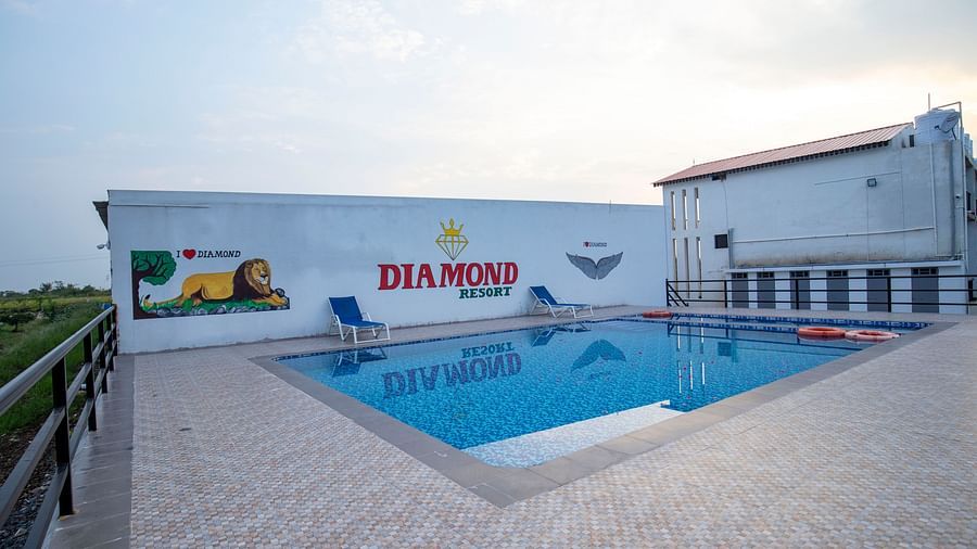 A pristine outdoor swimming pool with clear water and lounge chairs, set against a bright blue sky - VITS Select Diamond Resort, Sasan Gir