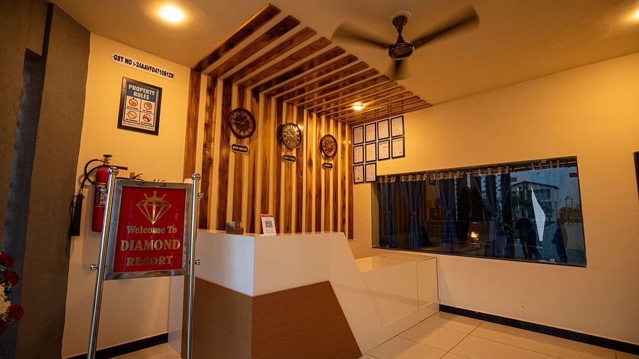 A reception area with wooden accents, featuring a desk and large windows, providing a warm and welcoming atmosphere - VITS Select Diamond Resort, Sasan Gir