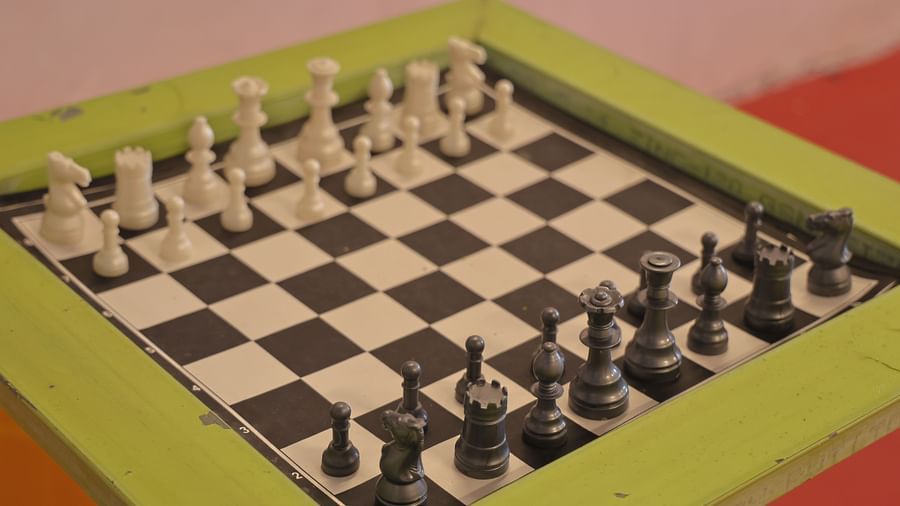 A close-up of a chess board with black and white chess pieces on a light green frame.