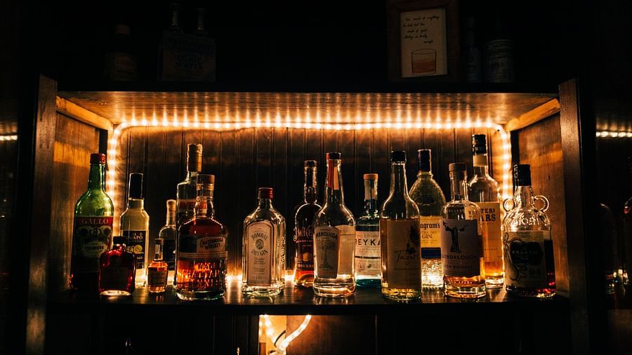 A dimly lit bar area with various bottles of spirits prominently displayed on illuminated shelves.