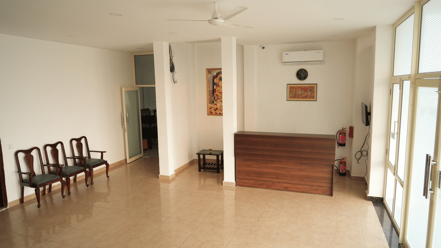 Spacious hotel lobby with a reception desk, seating area and large windows.