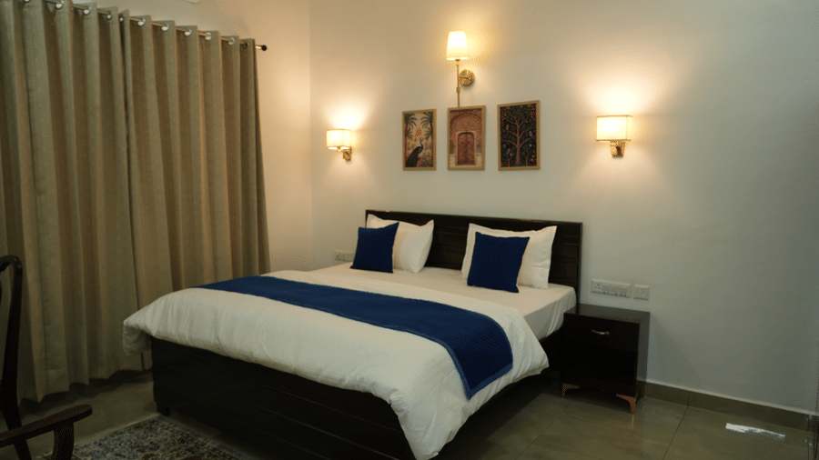 Room with a king size bed, blue accents, bedside tables and warm wall lighting.