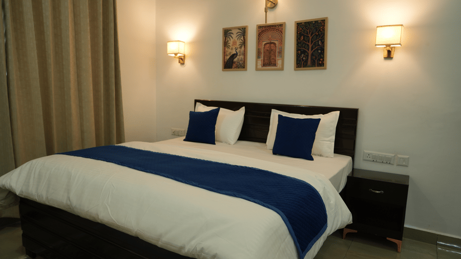 room featuring a king size bed with blue accents, bedside tables and framed artwork.