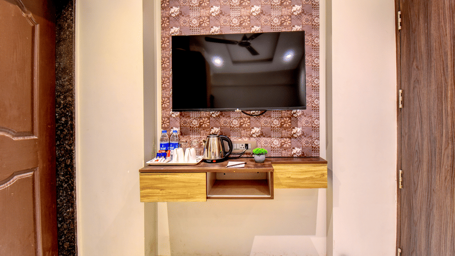 Classic Single Room wall-mounted TV with electric kettle, water bottles and tea tray on wooden console at VITS Select Kharadi Pune