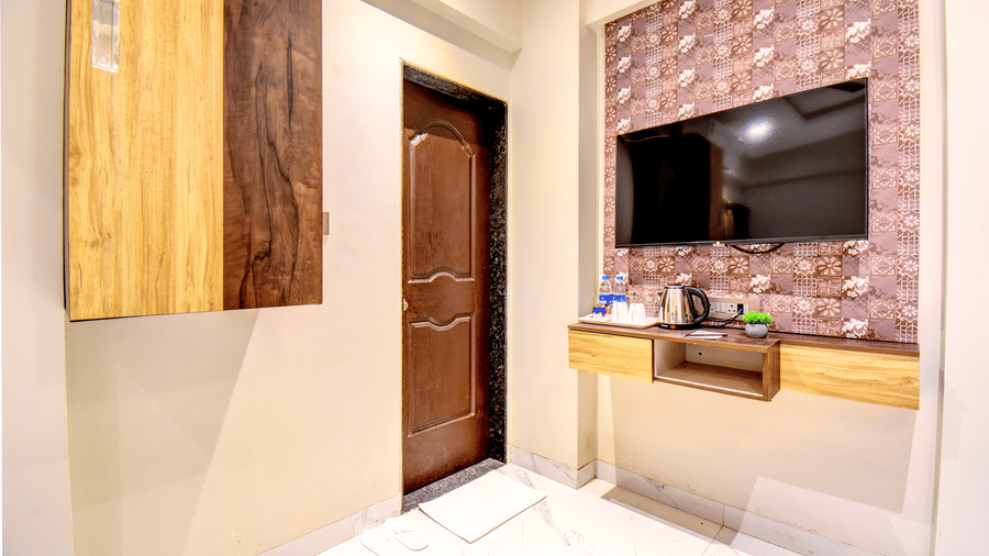 Classic Single Room TV unit with electric kettle, tea tray, decorative wall panel and wooden entry door at VITS Select Kharadi Pune