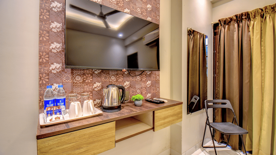 Deluxe Room TV unit with electric kettle, tea tray, water bottles and decorative wall panel at VITS Select Kharadi Pune