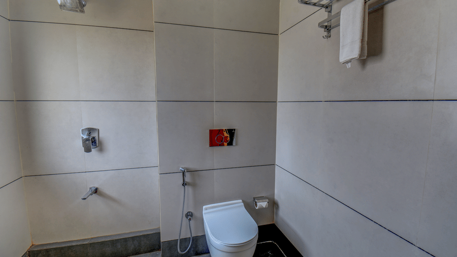 Bathroom shower area with tiled walls, fixtures, and toilet at VITS Select Nashik Hotels & Resorts.
