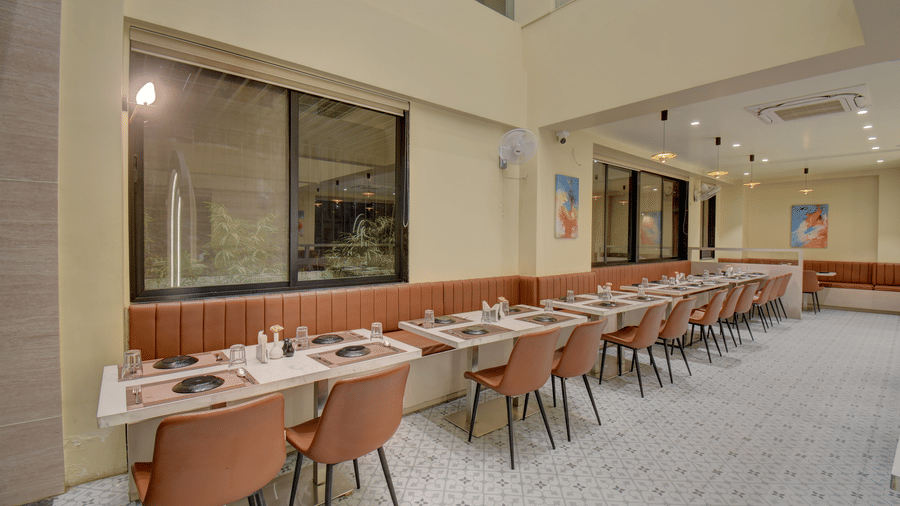 Long dining hall with neatly set tables and a calm, modern ambience at VITS Select Nashik Hotels & Resorts.